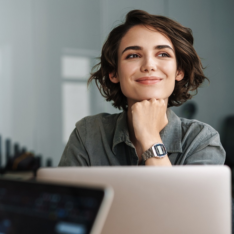 Ragazza felice di fronte al computer che sorride e guarda di lato